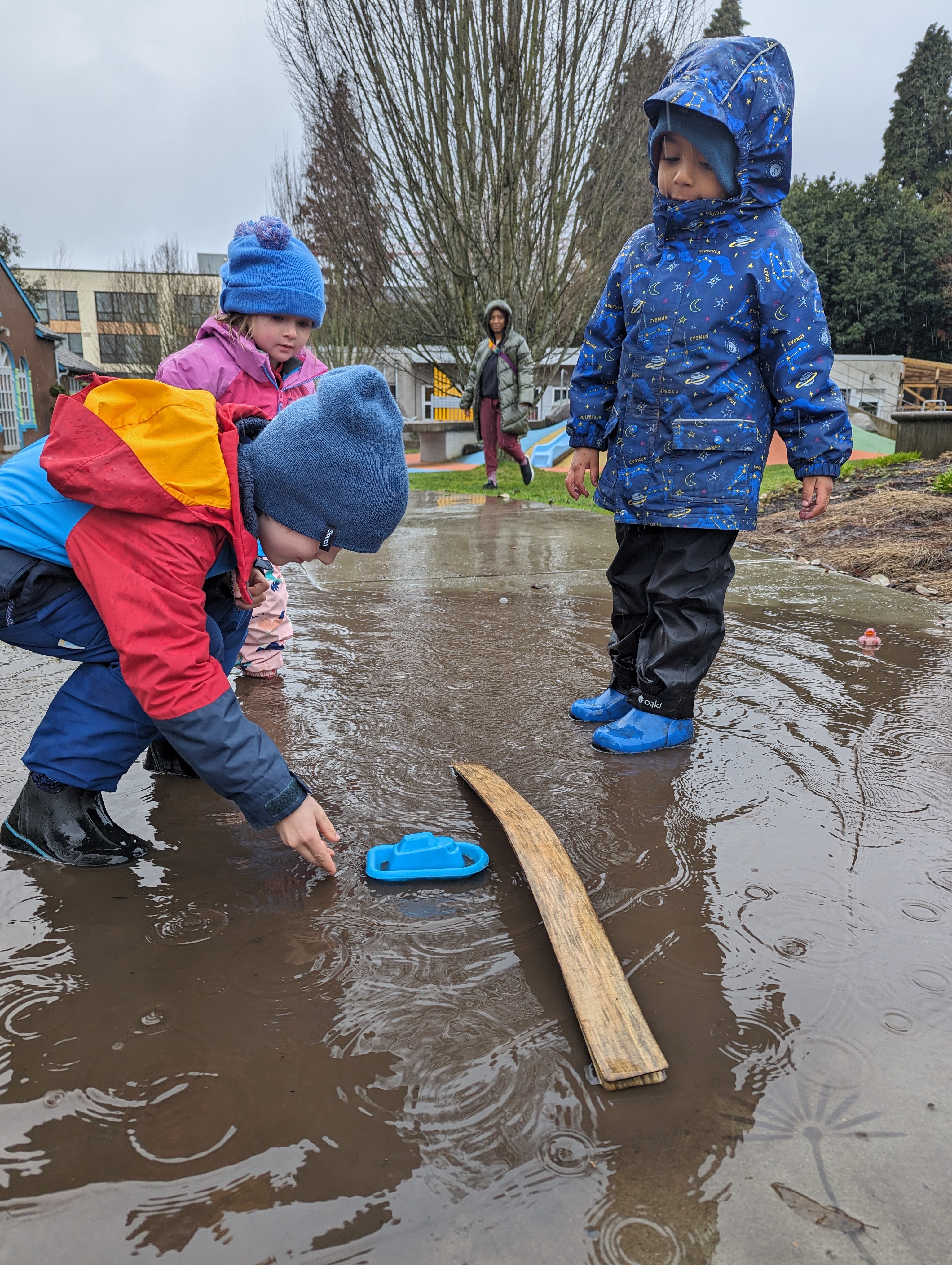 three children playing in a puddle